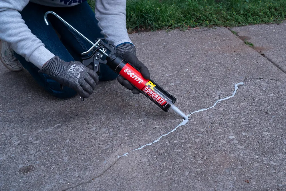 Person using LOCTITE® PL Self-Leveling Sealant to repair pavement crack