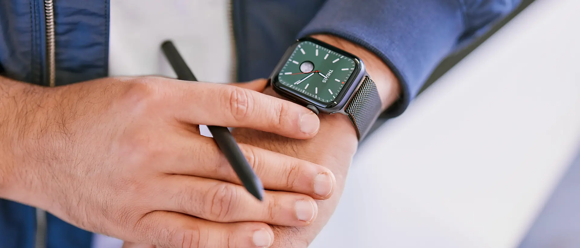 Eine Nahaufnahme eines Mannes, der auf eine schwarze Smartwatch an seinem linken Handgelenk schaut.