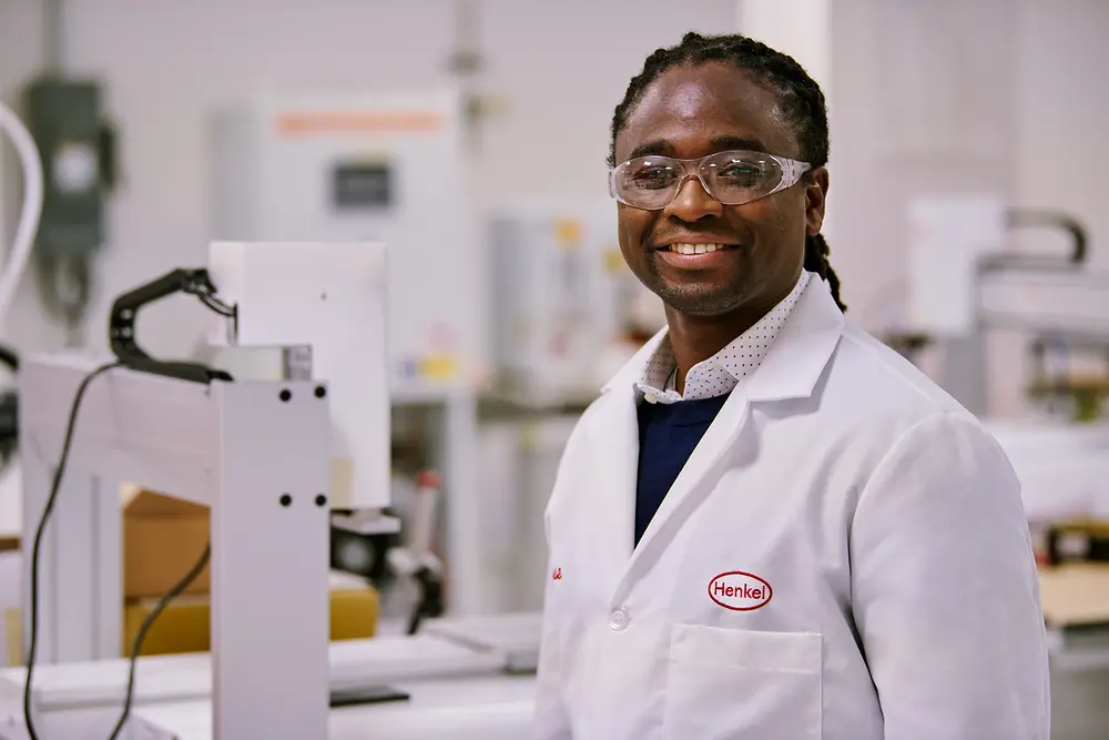 Ein Wissenschaftler in einem Henkel-Labor, der eine Schutzbrille und einen Laborkittel trägt und in einer modernen Einrichtung arbeitet.