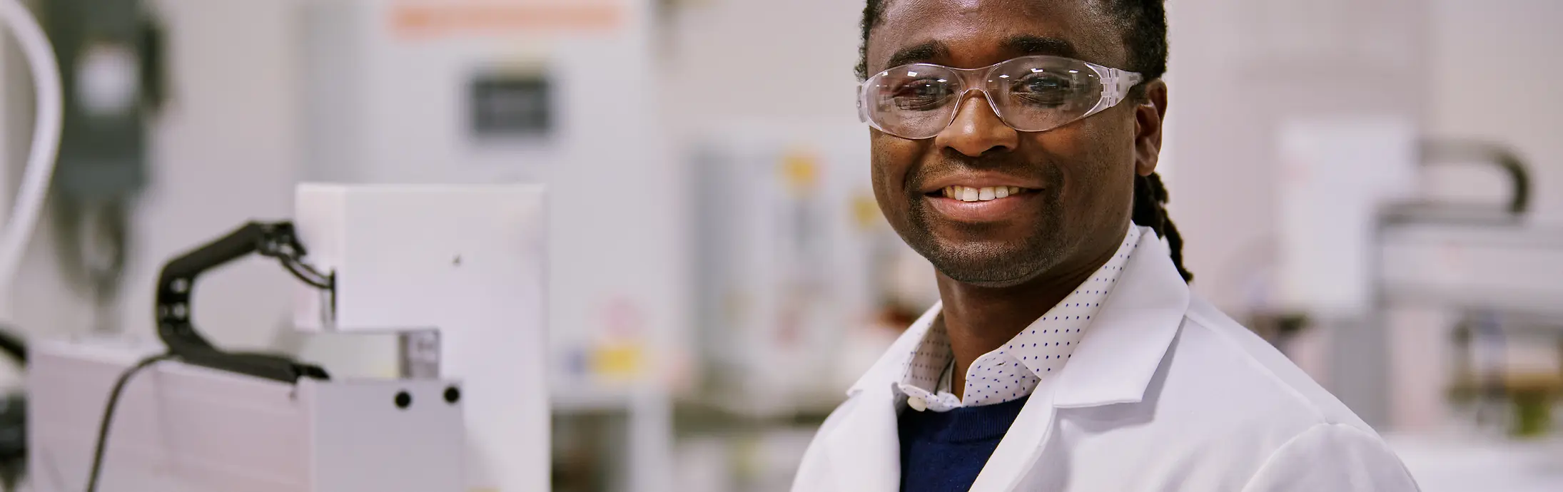 Ein Wissenschaftler in einem Henkel-Labor, der eine Schutzbrille und einen Laborkittel trägt und in einer modernen Einrichtung arbeitet.